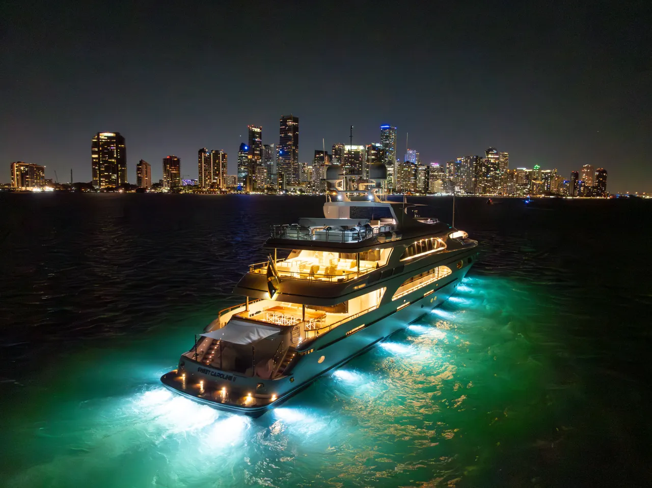 A BillsIn Yachts luxury charter yacht lit up in the evening